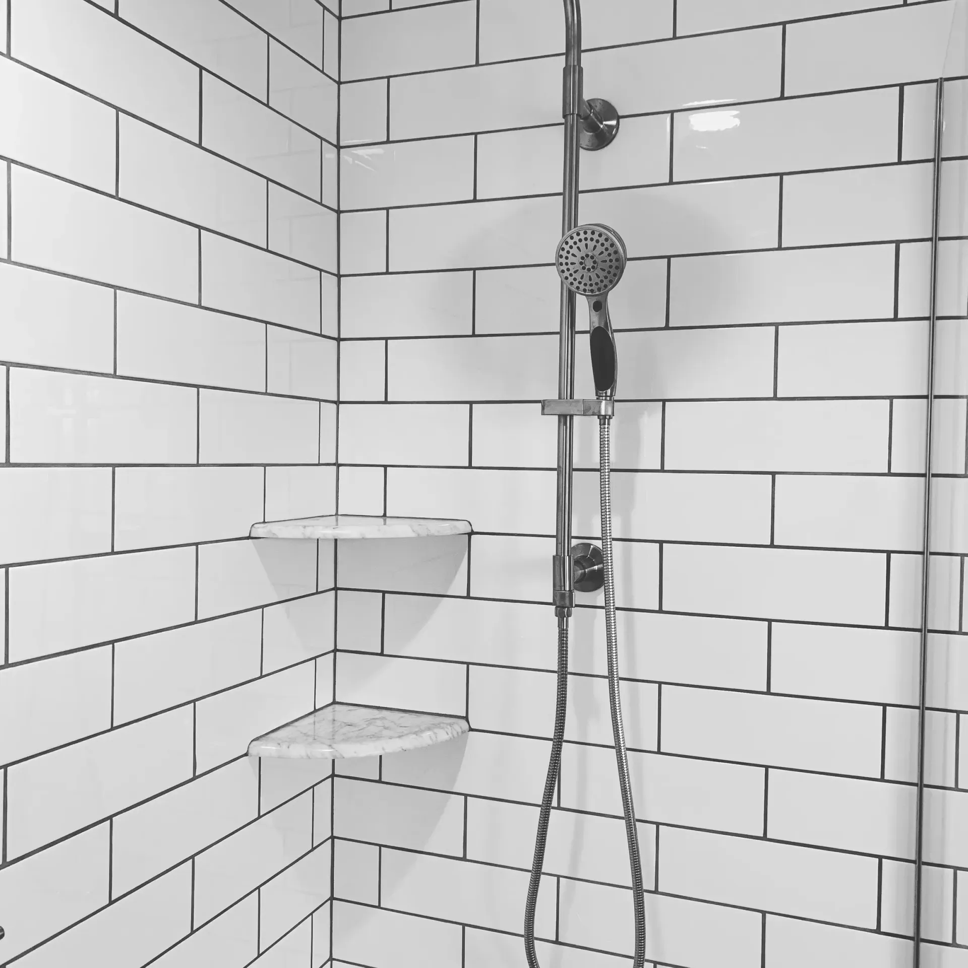 A shower with white tiles and a shower head
