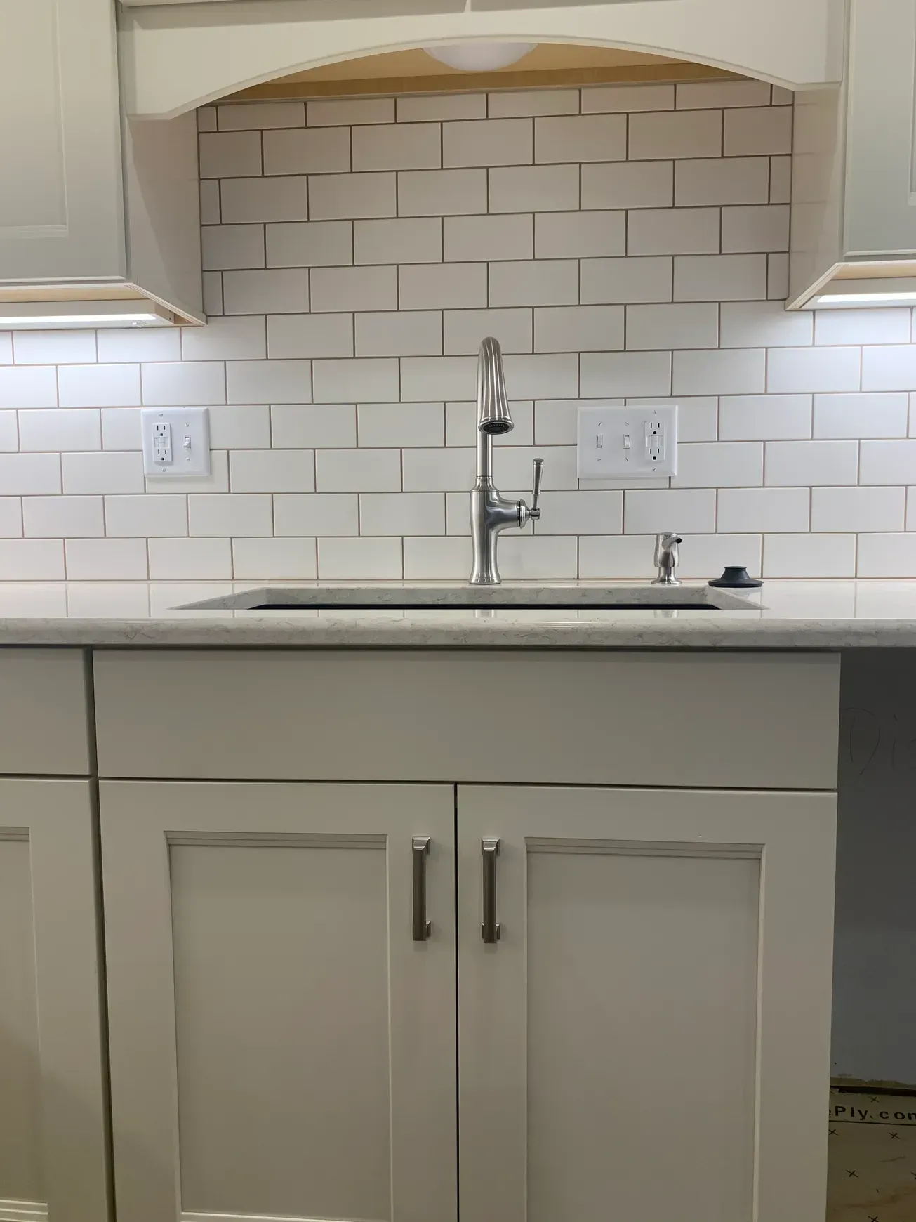 A kitchen with white cabinets and a sink with a faucet