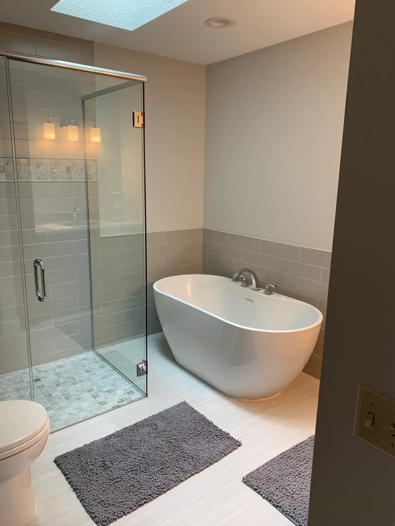 A bathroom with a tub , toilet , shower and skylight.