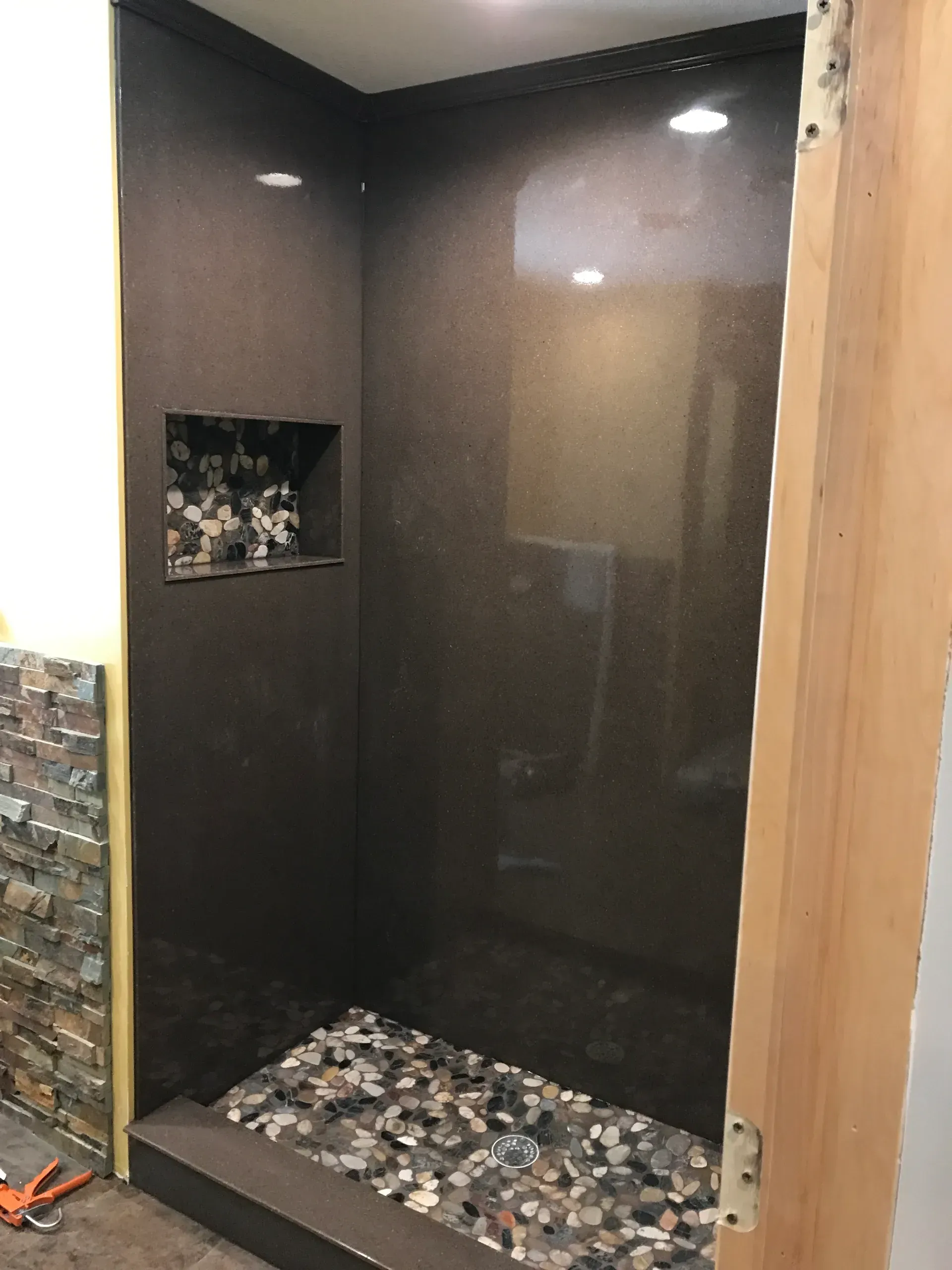 A bathroom with a walk in shower and a wooden door.