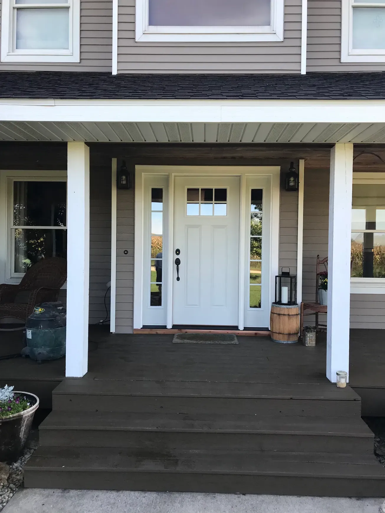 The front door of a house with a porch and a white door.