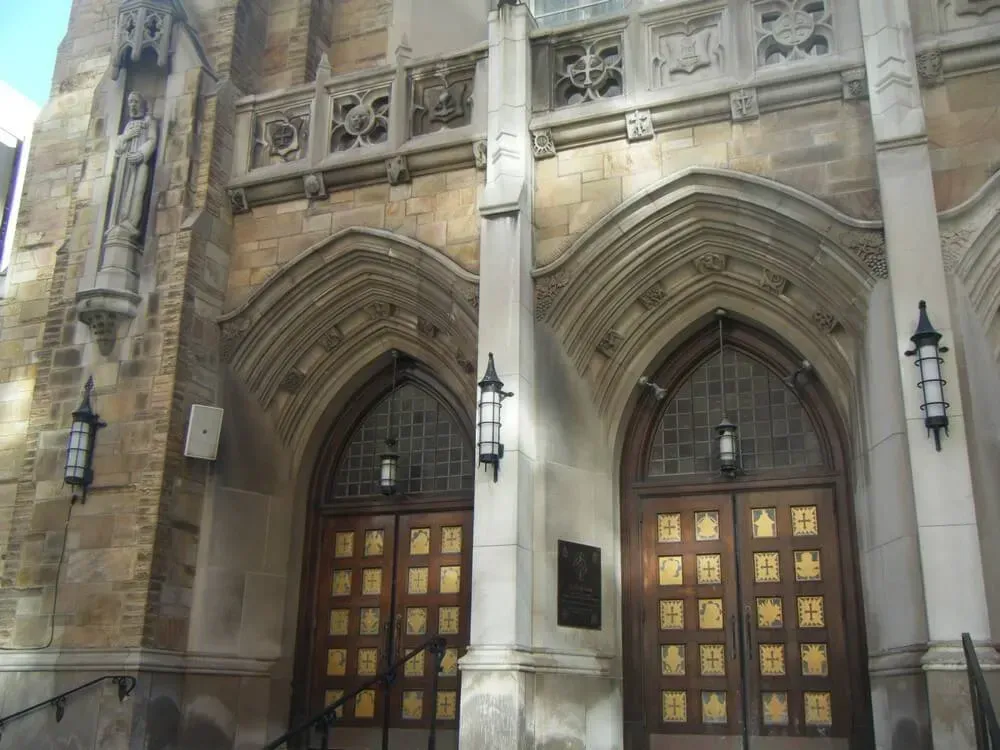 Stone church entrance with arched doors, gold details, and decorative stonework.