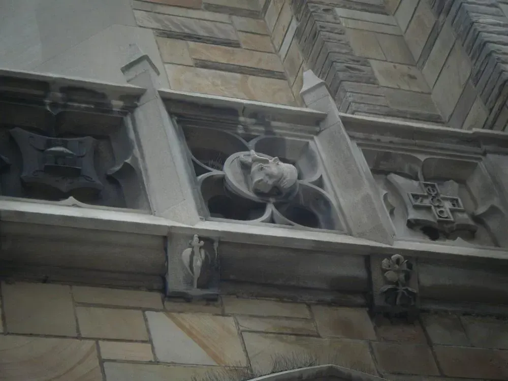 Stone carvings on building facade. Close up shows floral and cross motifs.