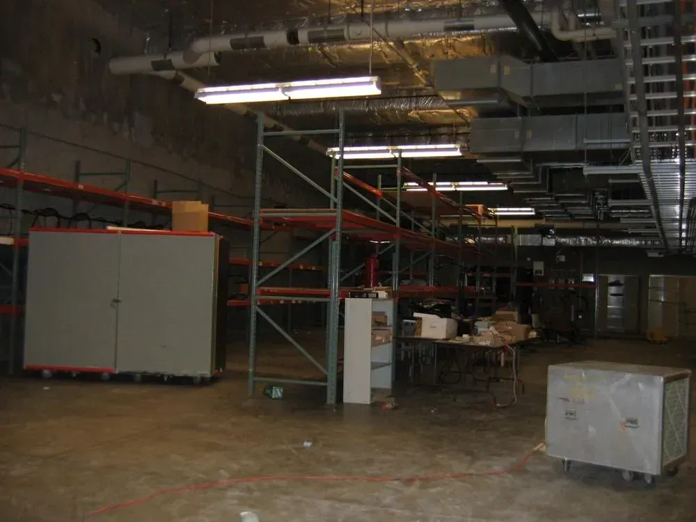 Empty warehouse interior with metal shelving, cabinets, and a table.