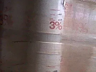 Close-up of a light-colored cylinder, possibly a barrel, with a 