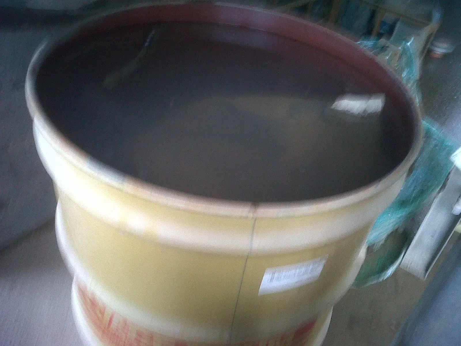 A yellow barrel filled with murky, brown liquid.