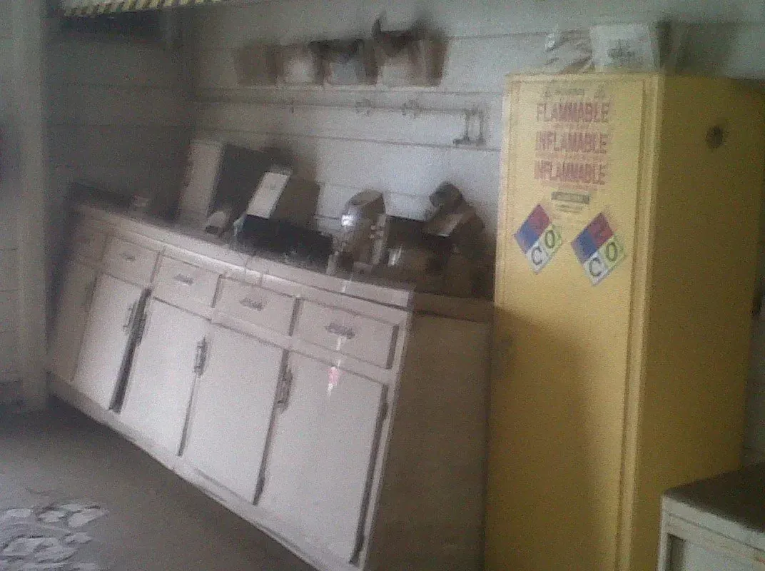 Dilapidated kitchen: yellow cabinet, off-white cabinets, old appliances, peeling paint.