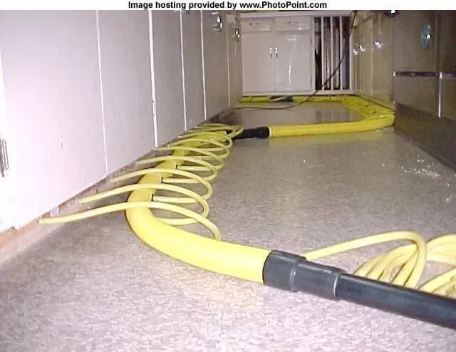 Yellow hose looped along a kitchen floor, likely for cleaning.