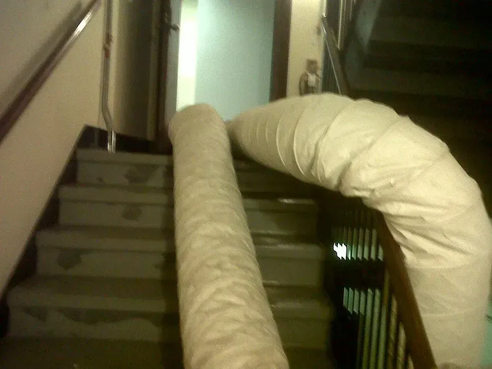 Rolled carpet in protective wrap on an interior staircase, blocking access.