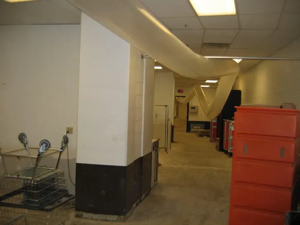 Hallway with white walls, a large vent, and red storage containers.