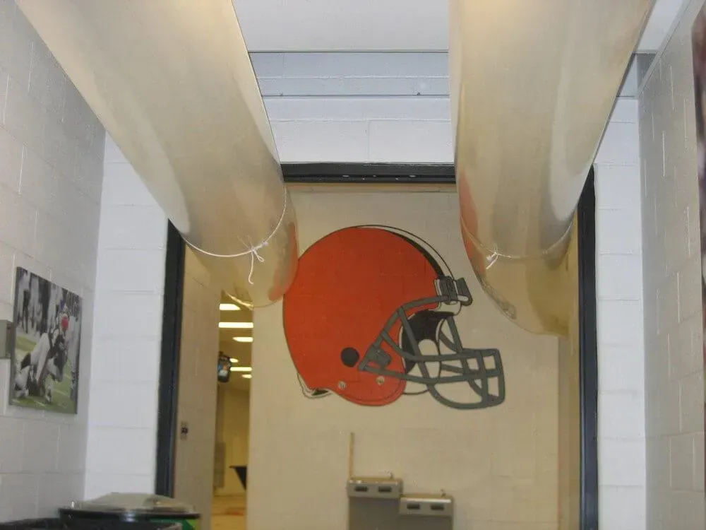 Brown Cleveland Browns helmet logo on a wall, flanked by curved ceiling features.