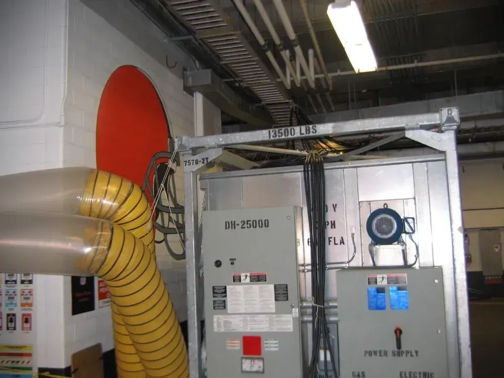 Electrical panel with conduits and ductwork. Orange wall circle, gray metal frame, overhead lighting.