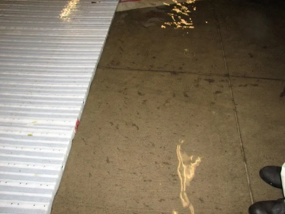 Gray, corrugated surface next to a wet, concrete floor.