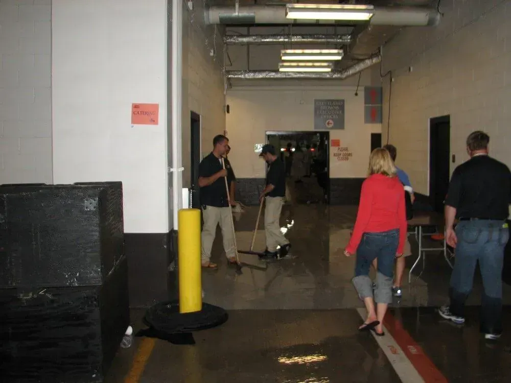 People standing in a flooded hallway, with some sweeping water.
