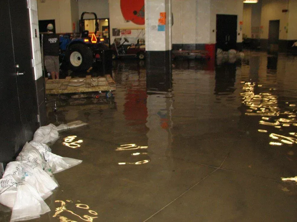 Interior room flooded with brown water; a tractor, papers, and columns are visible.