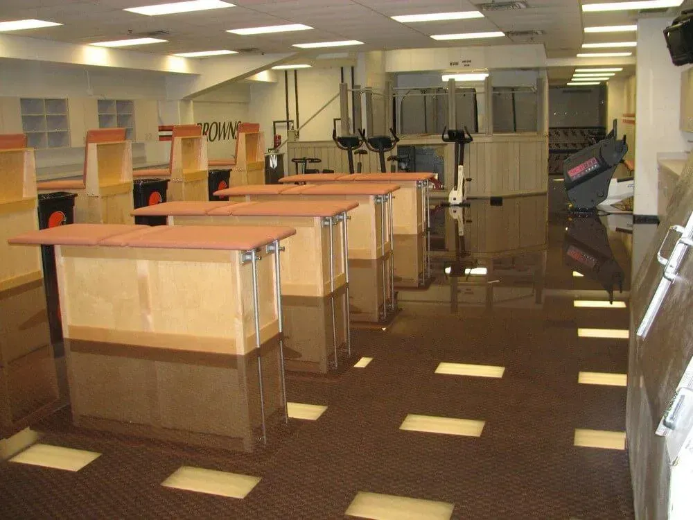 Brown room with multiple wooden carts and reflective flooring; likely an empty storage or processing area.