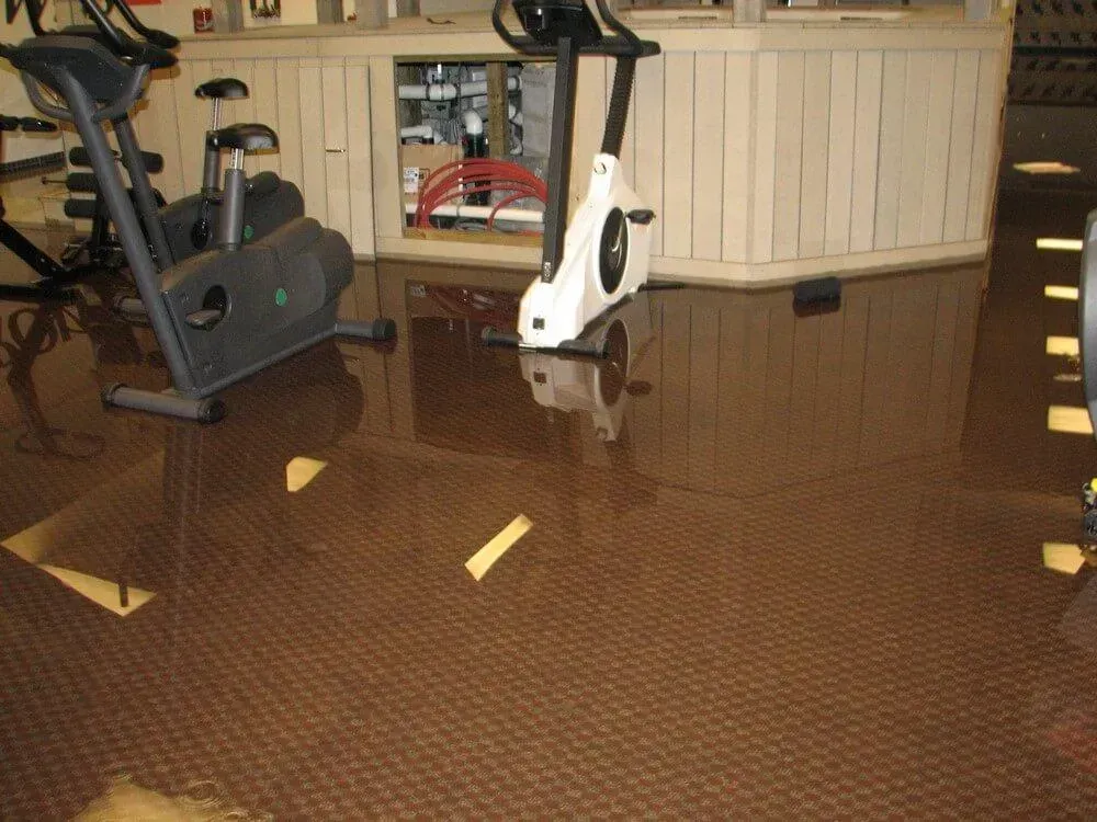 Gym flooded with brown water, exercise bikes partially submerged.