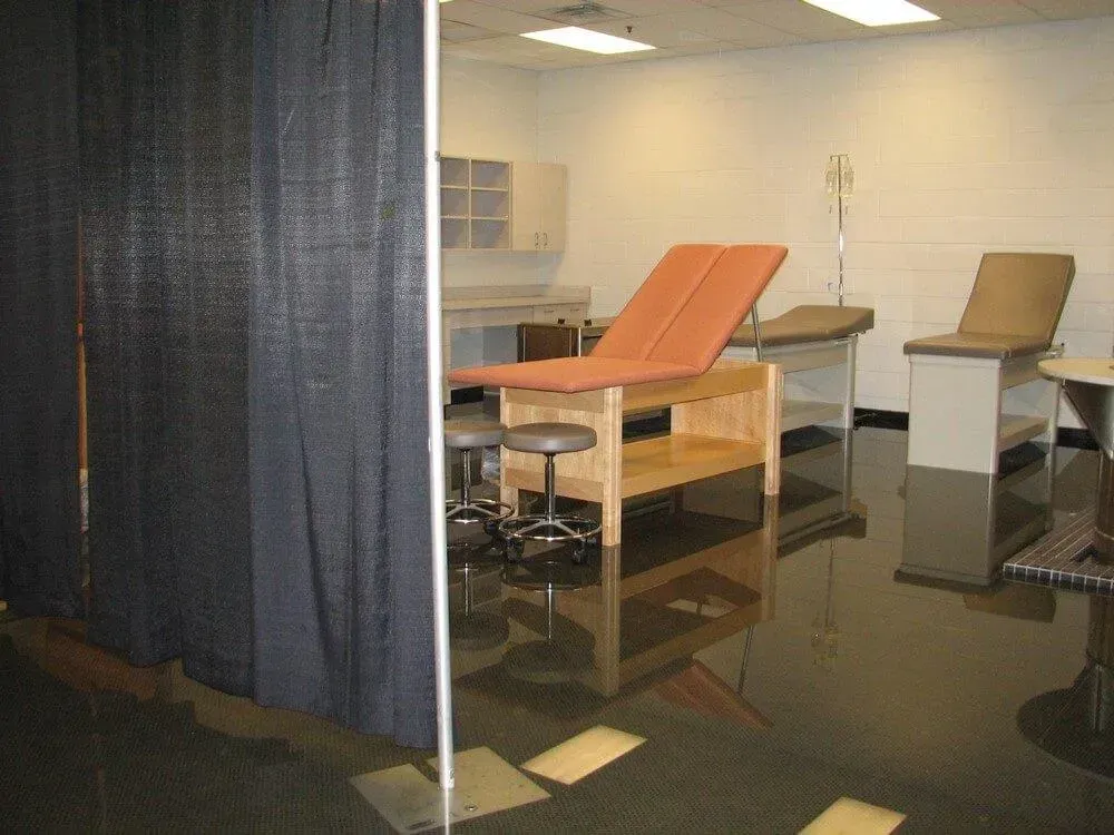 Medical examination room with exam tables, stools, and privacy curtain.