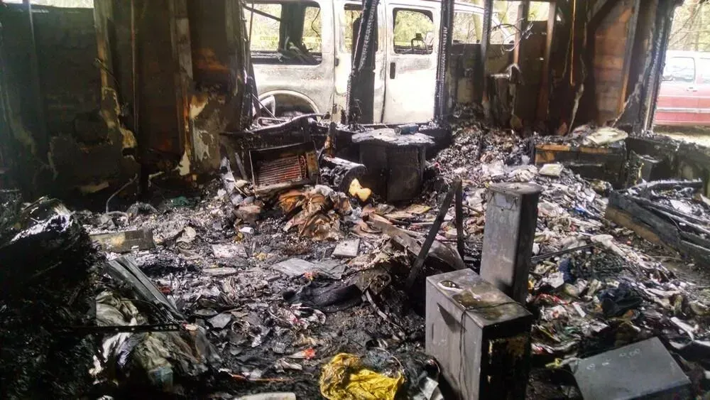 Interior of a vehicle destroyed by fire, showing charred remains and debris.