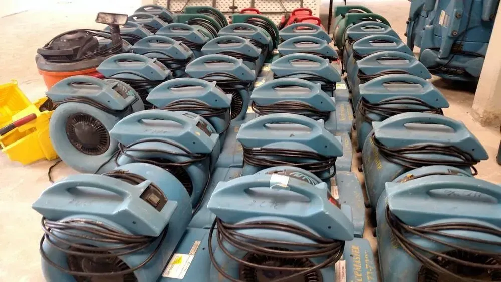 Rows of teal air movers on a floor, possibly for water damage restoration.