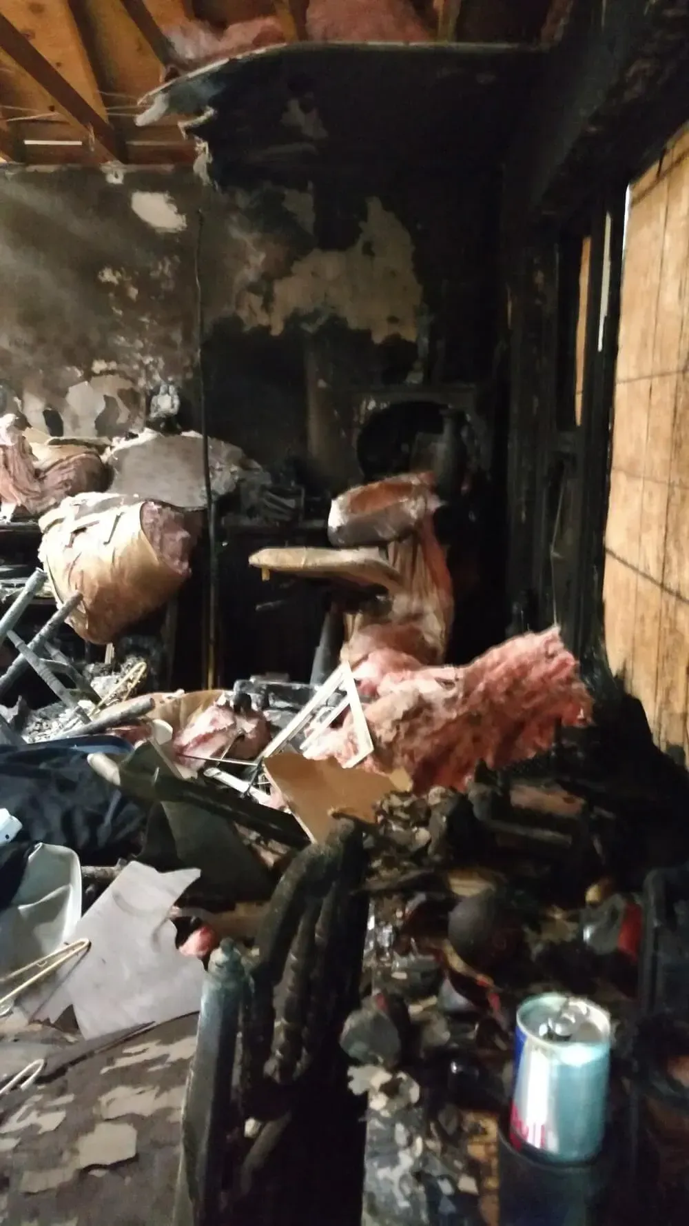 Interior of a room destroyed by fire; charred walls and debris, remnants of furniture, scorched insulation.