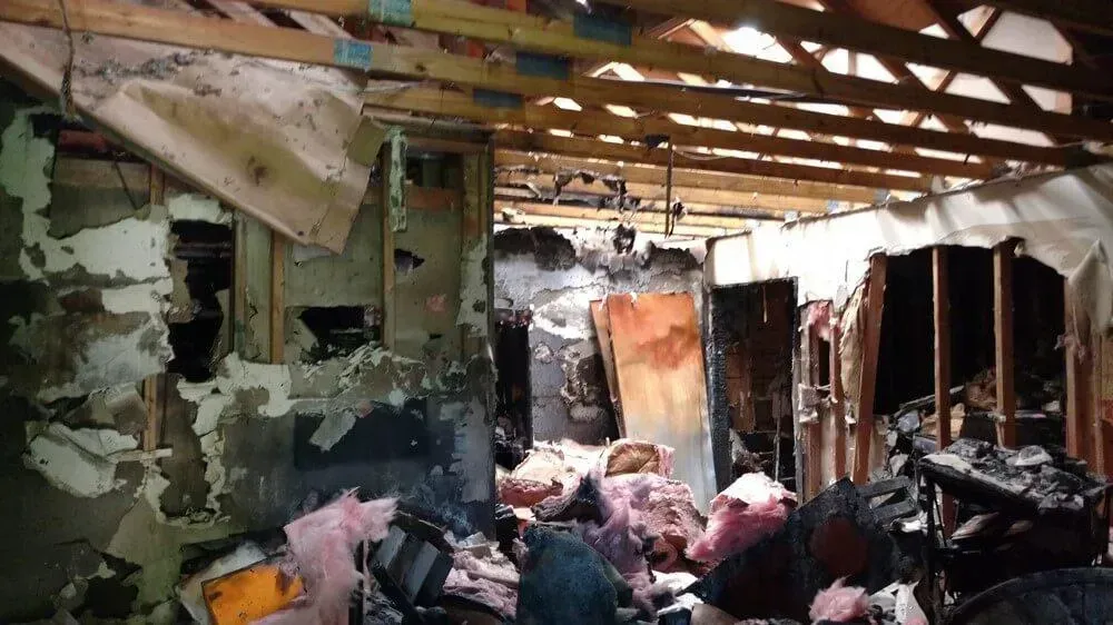 Interior of a building damaged by fire; charred walls, debris, and exposed framing.