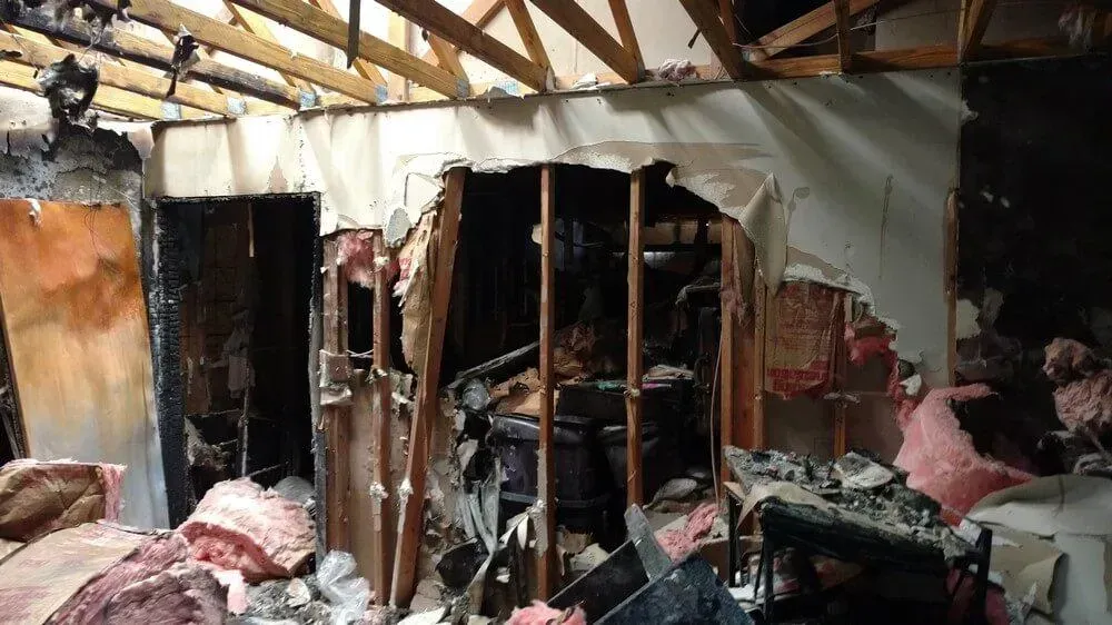 Interior of a room destroyed by fire; charred walls and debris, exposed framing and insulation.