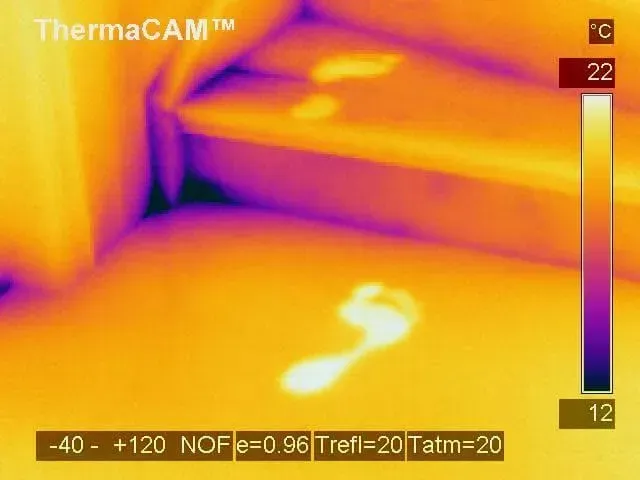 Thermal image of footprints on a surface, showing heat signatures. Yellow and purple indicate temperature variation.