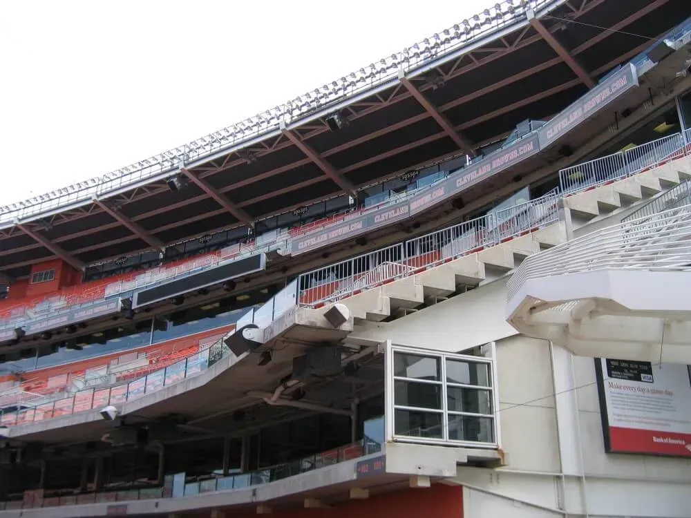 Stadium seating, multiple tiers, empty; partial view of an exterior wall with windows.