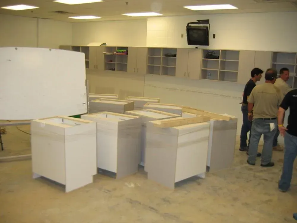 Cabinets and men in a room, cabinets in front, wall cabinets above.