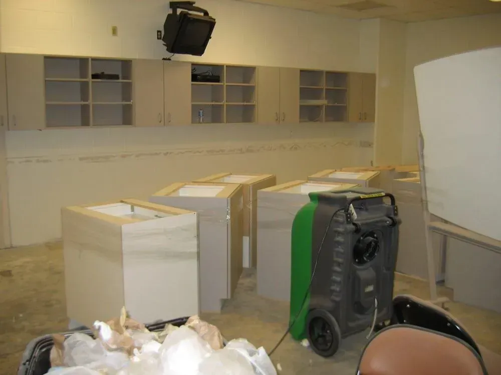 Empty room with several unfinished counters, cabinets, and a dehumidifier.