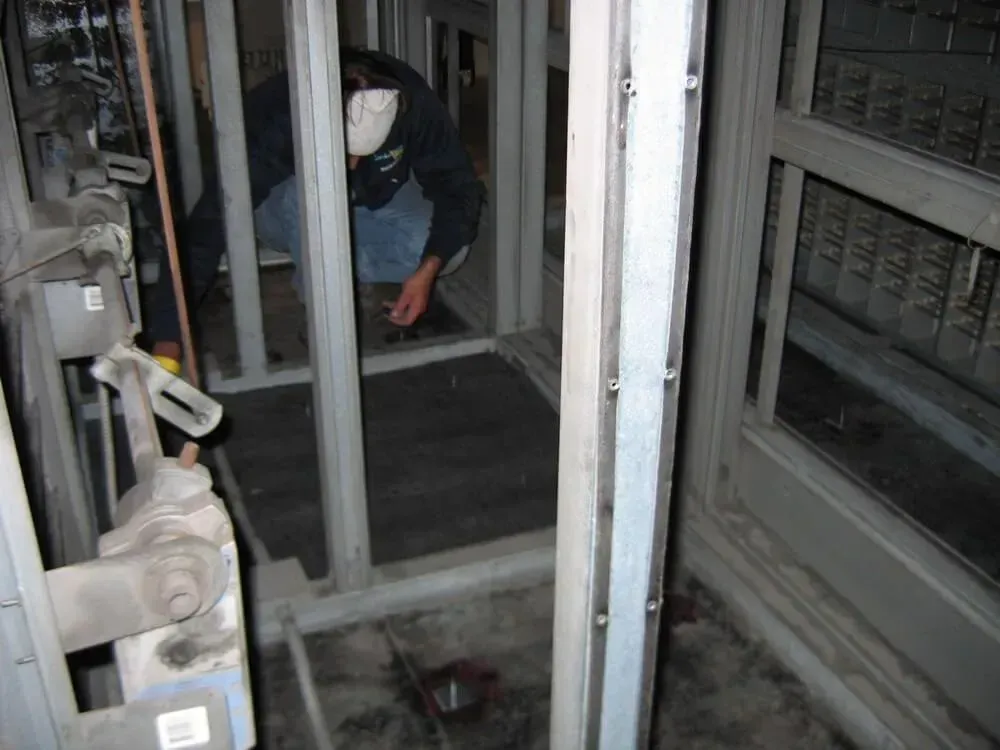 Person working inside a metallic structure with exposed wiring, possibly construction or repair.