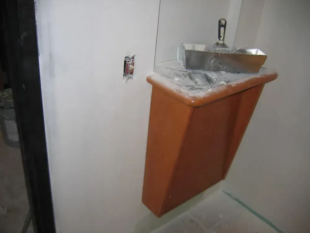 Orange cabinet attached to a white wall, with drywall tools on top, near an electrical outlet.