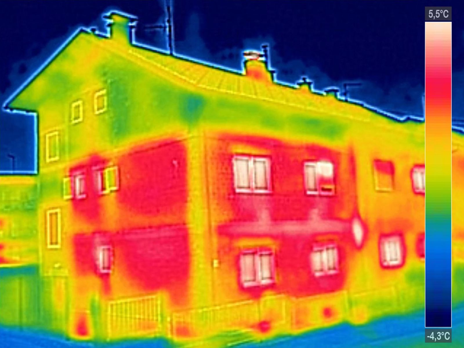 Thermal image of a building; warm colors (red/yellow) indicate heat loss through walls and roof.