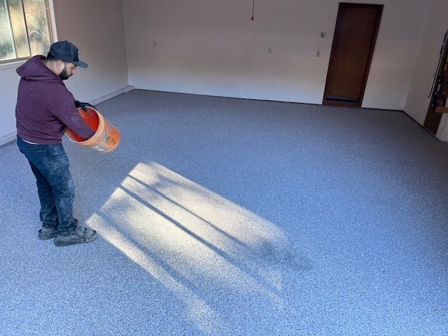 Person pours coating on a speckled floor in a garage.