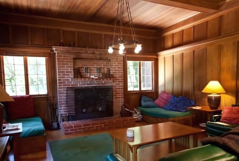 A living room with a brick fireplace and wood paneling