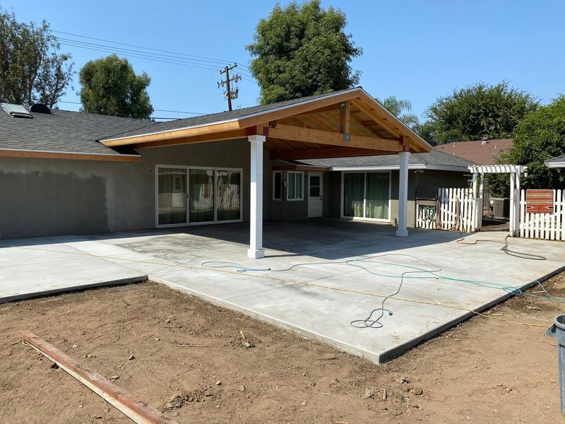 Backyard patio with a new concrete slab and covered roof extension beside a house
