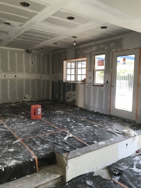 Unfinished room with drywall, taped floor, exposed ceiling, windows, and a temporary step platform