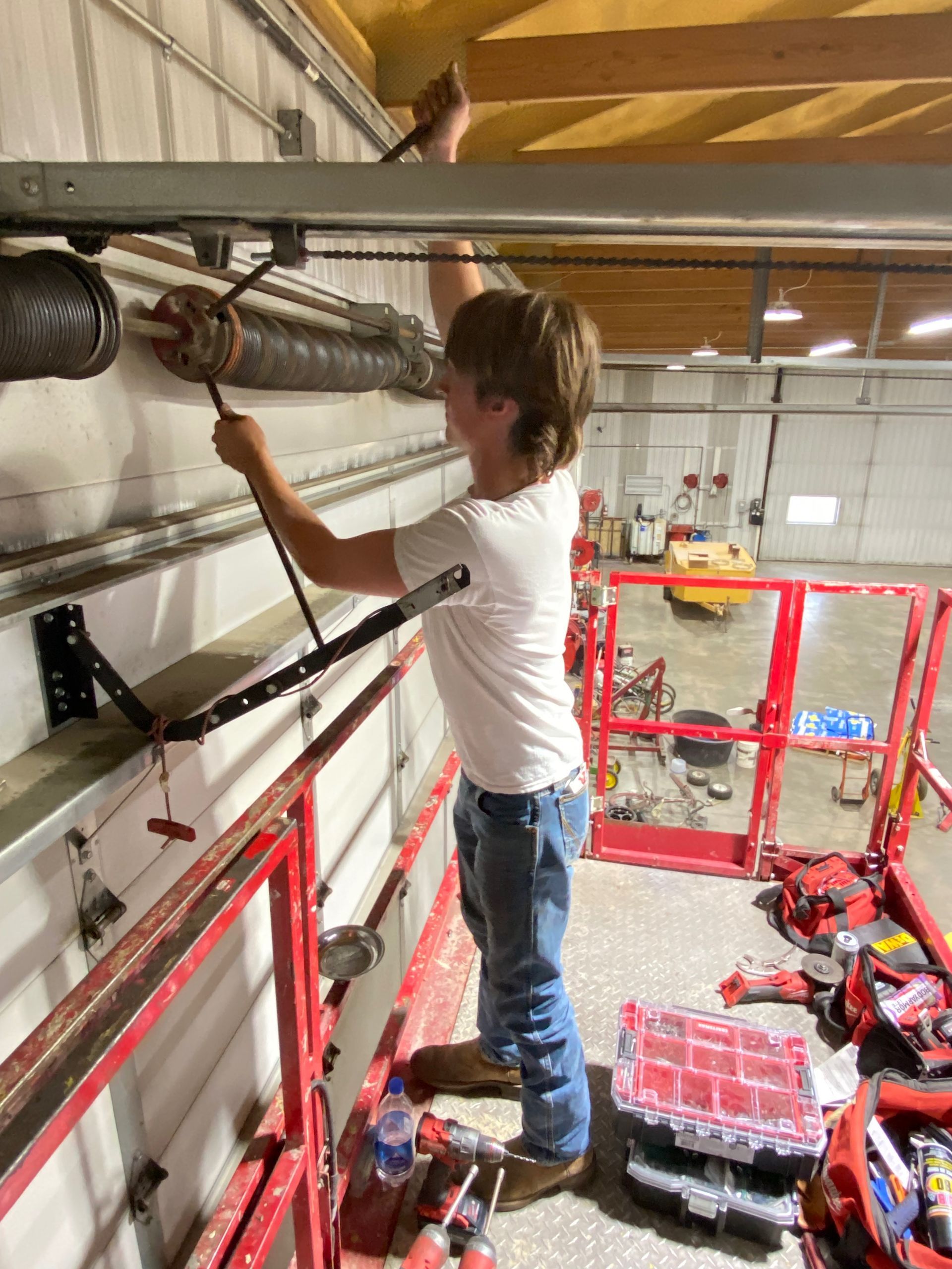 A man is standing on a lift working on a pipe.