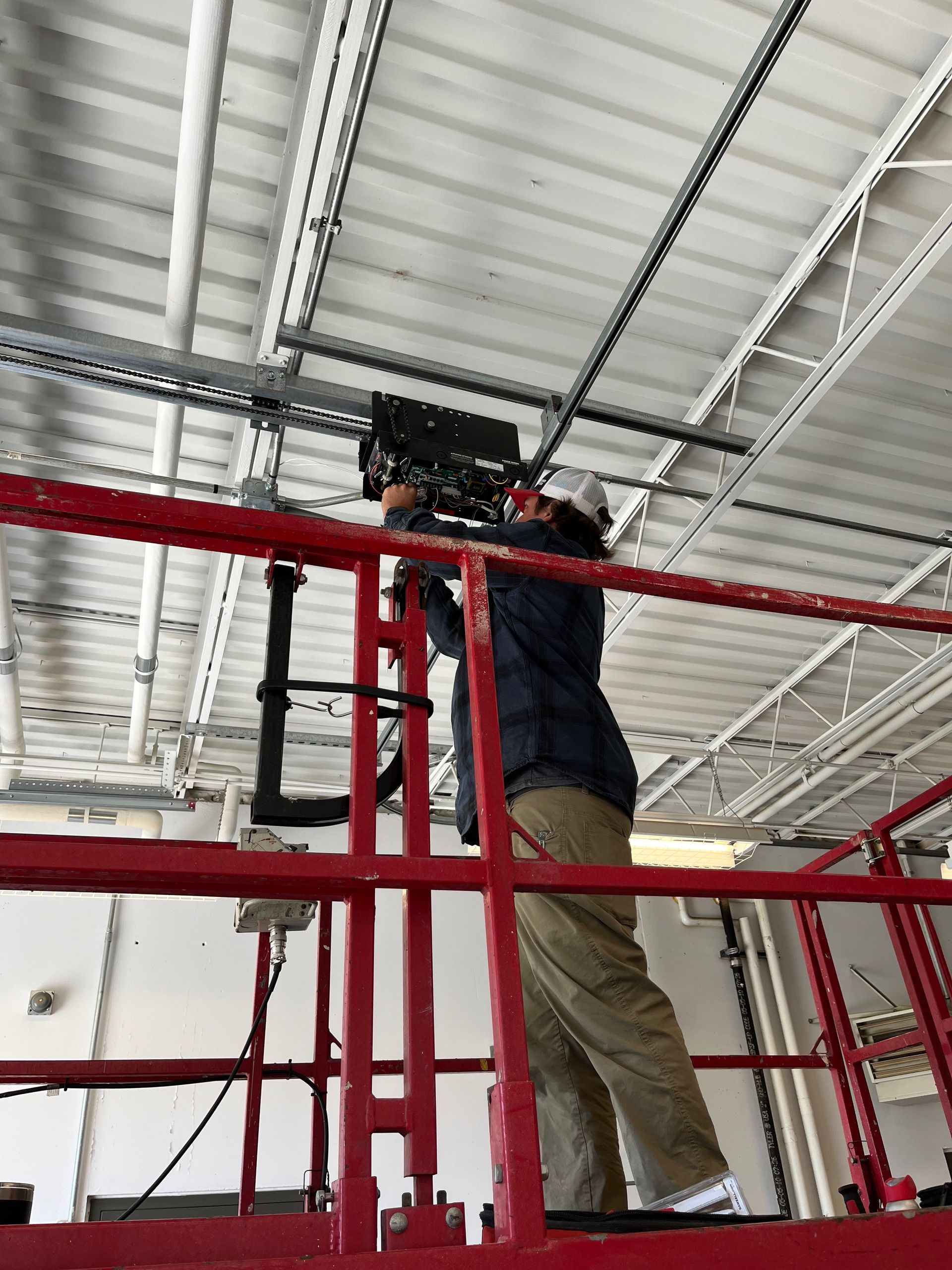 A man is standing on a lift working on a ceiling.