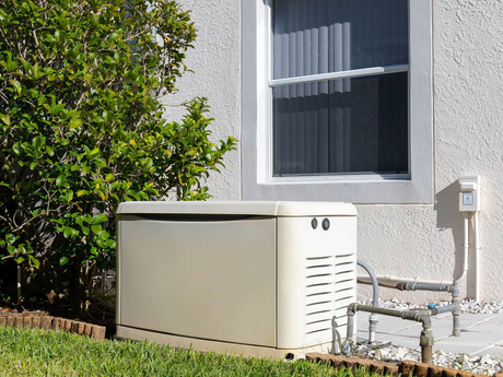 Standby generator next to a house with a window and gas lines.