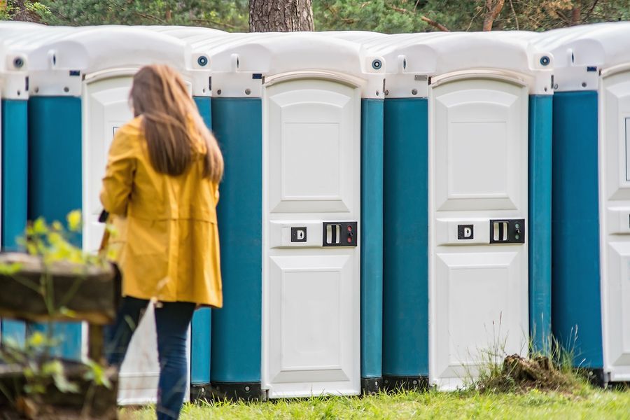 A woman is standing in front of a row of portable toilets.