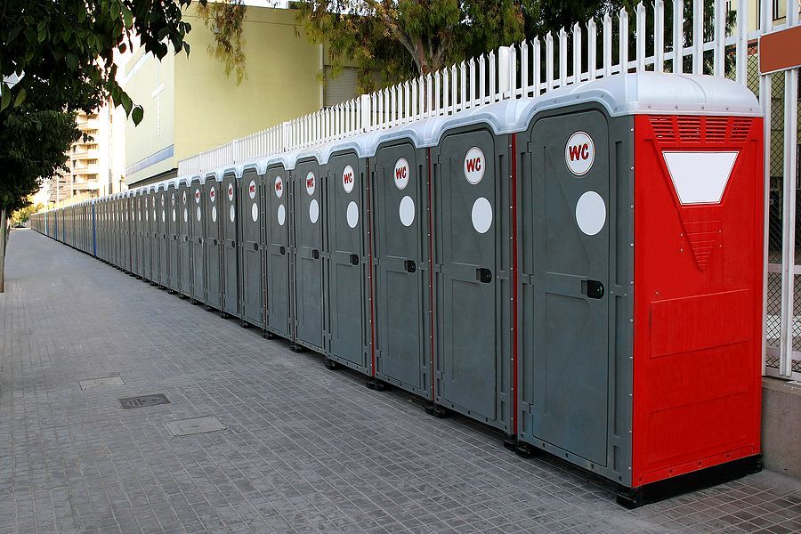 A row of portable toilets are lined up on a sidewalk