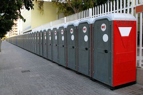 A row of portable toilets are lined up on a sidewalk