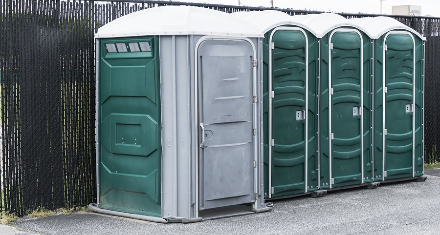 A row of green portable toilets are lined up next to each other