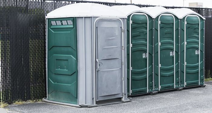 A row of green portable toilets are lined up next to each other
