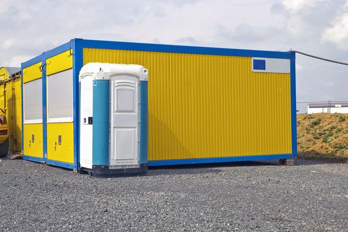 A blue and yellow building with a portable toilet in front of it