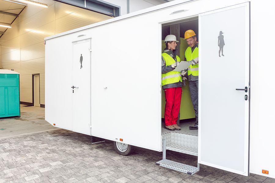 Two construction workers are standing outside of a trailer looking at a clipboard.