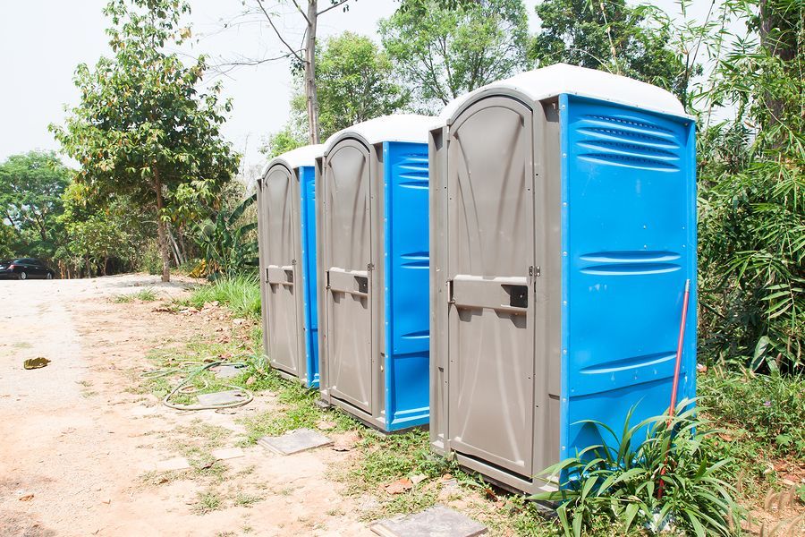 A row of blue and grey portable toilets in a field