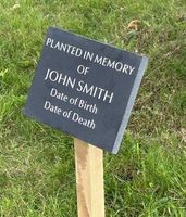 A memorial sign for john smith is sitting in the grass.